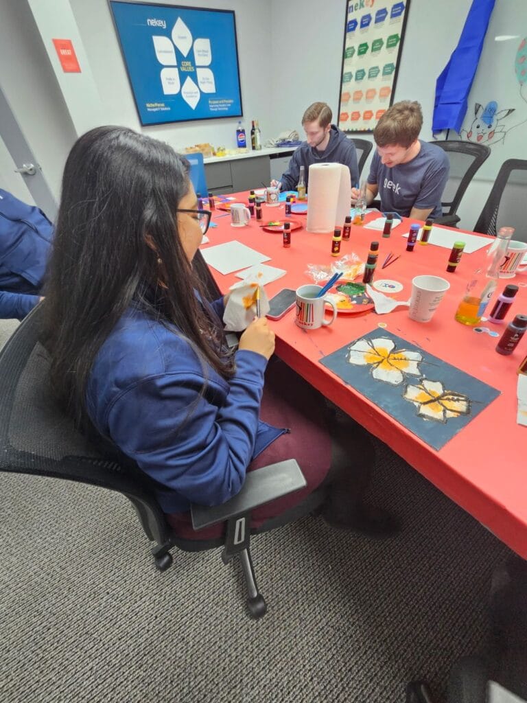 participants painting flower canvases at a Culture Club paint and sip event in an office conference room